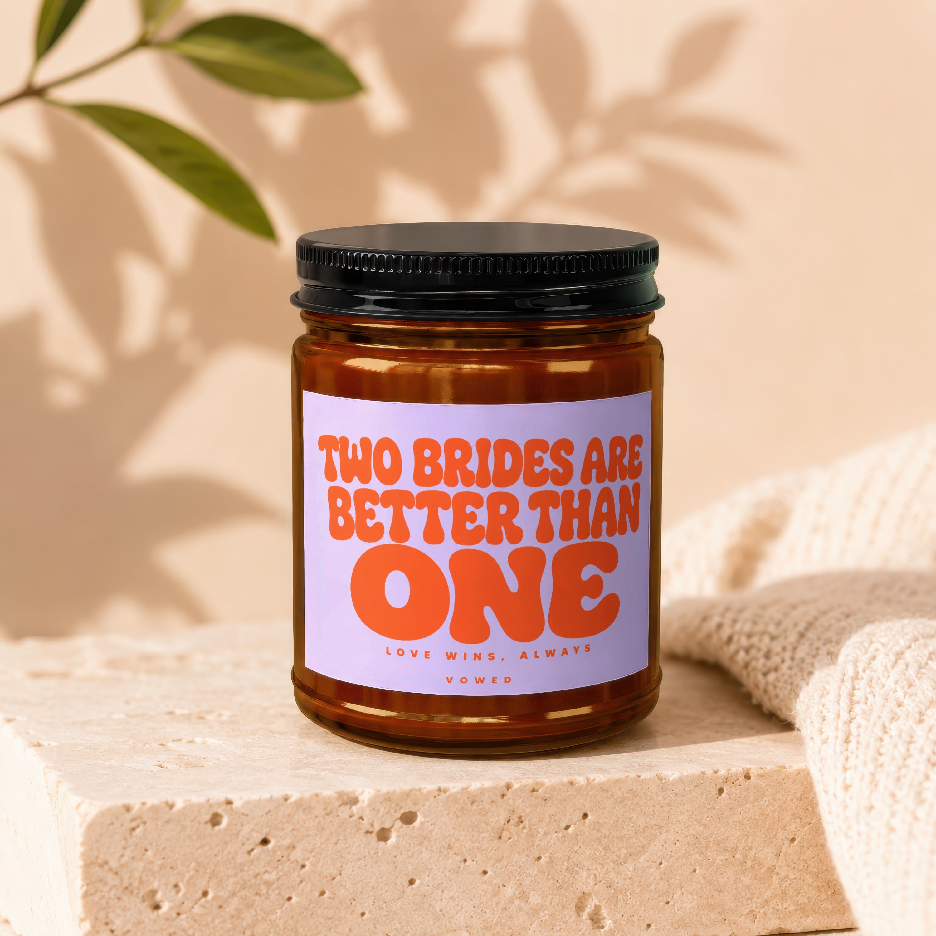 Brown glass candle with orange text reading "TWO BRIDES ARE BETTER THAN ONE LOVE WINS, ALWAYS VO WED".
