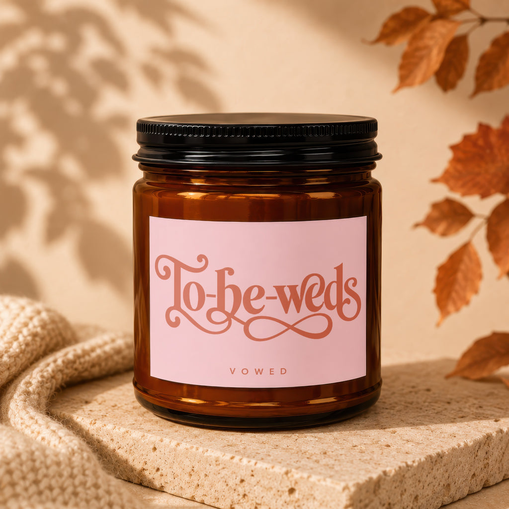 Amber glass candle with pink label reading "To-be-weds VOWED".