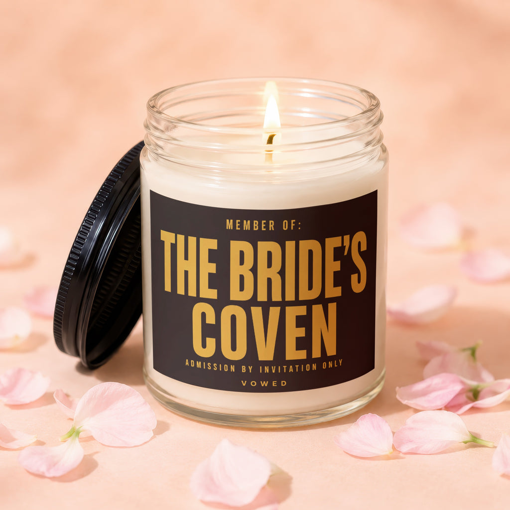 Scented candle with label "Member of: The Bride's Coven" surrounded by pink petals.