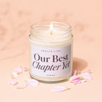 Scented candle with text "Our Best Chapter Yet" surrounded by pink petals.
