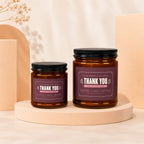 Two amber glass candles with "Thank You for Raising Him" labels on purple backgrounds.