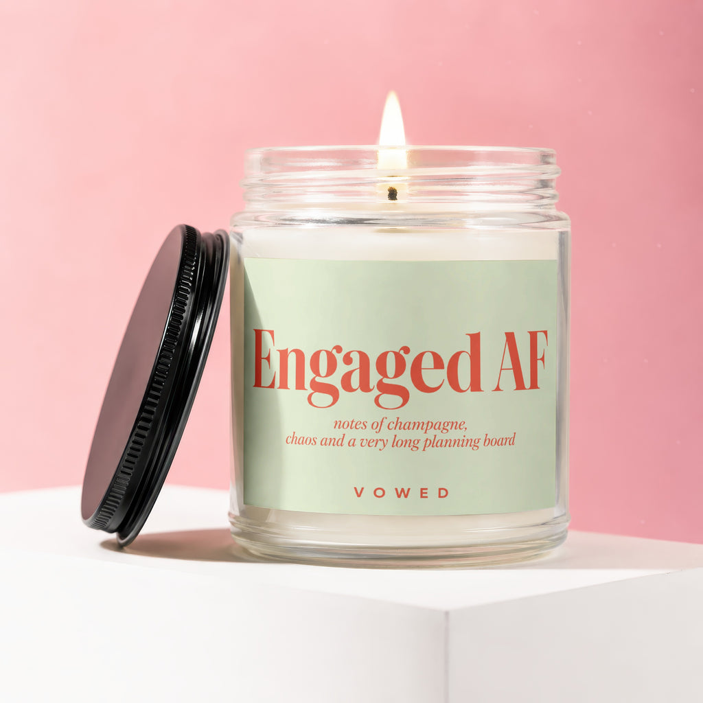 Glass candle with lid off, labeled "Engaged AF" and "Vowed".