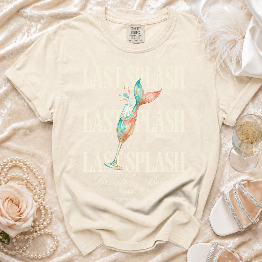 Cream t-shirt with "LAST SPLASH" and mermaid tail in champagne glass.