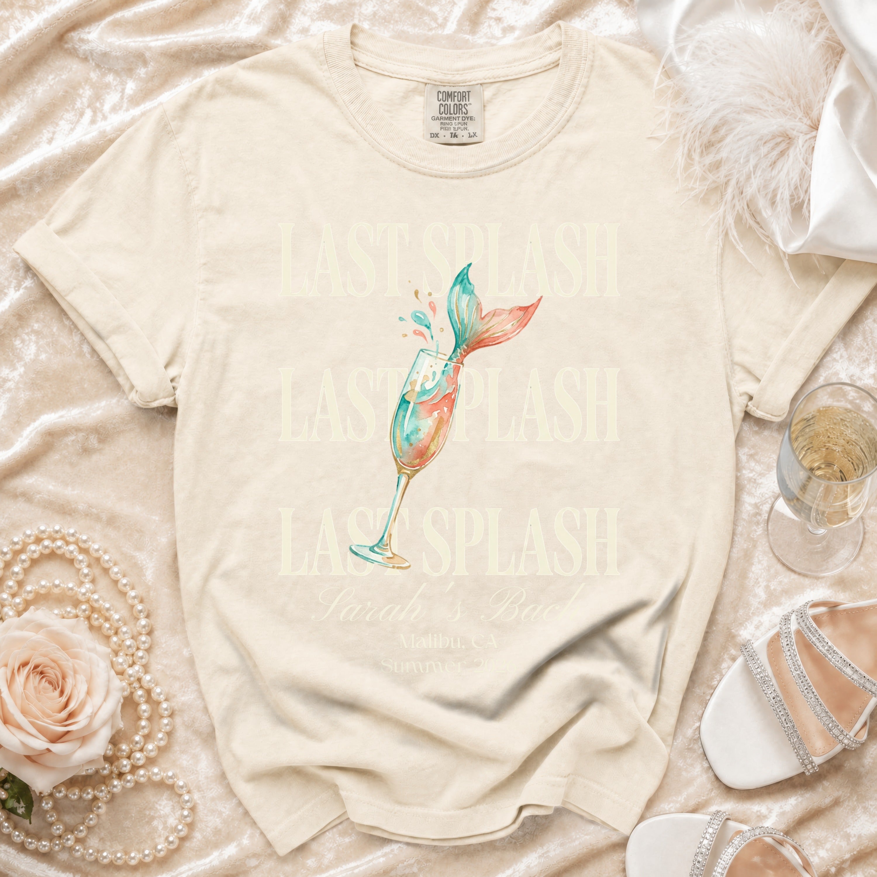 Cream t-shirt with "LAST SPLASH" and mermaid tail in champagne glass.