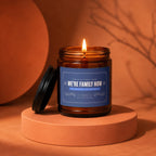 Amber jar candle with lit flame and label that reads "We're Family Now".