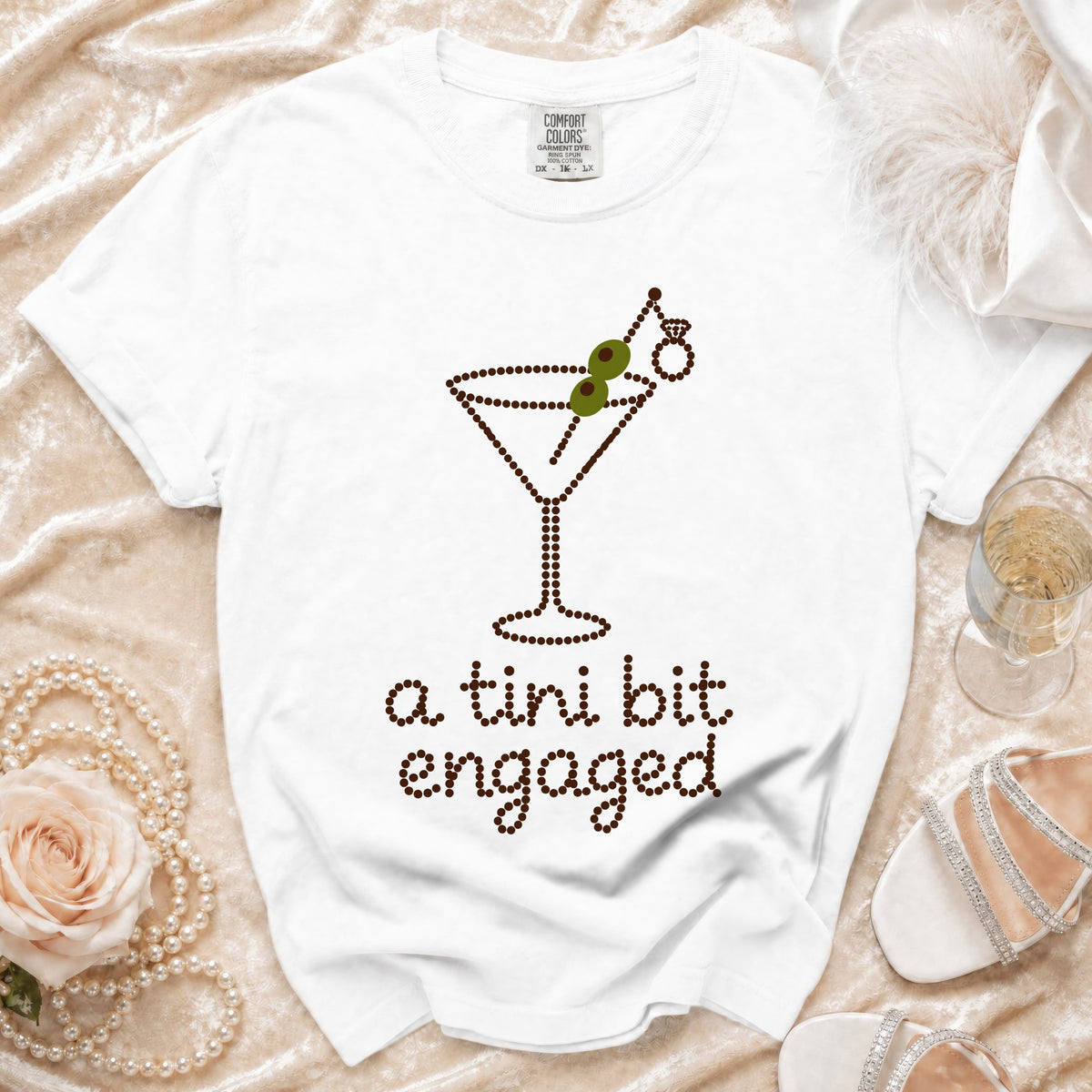 White t-shirt with rhinestone martini glass, ring, and "a tini bit engaged" text.