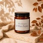 Brown glass candle with black lid, reads "We Eloped. It Was Perfect."