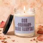 Candle with "Our Ordinary Dark Fairytale" text burns next to its lid.