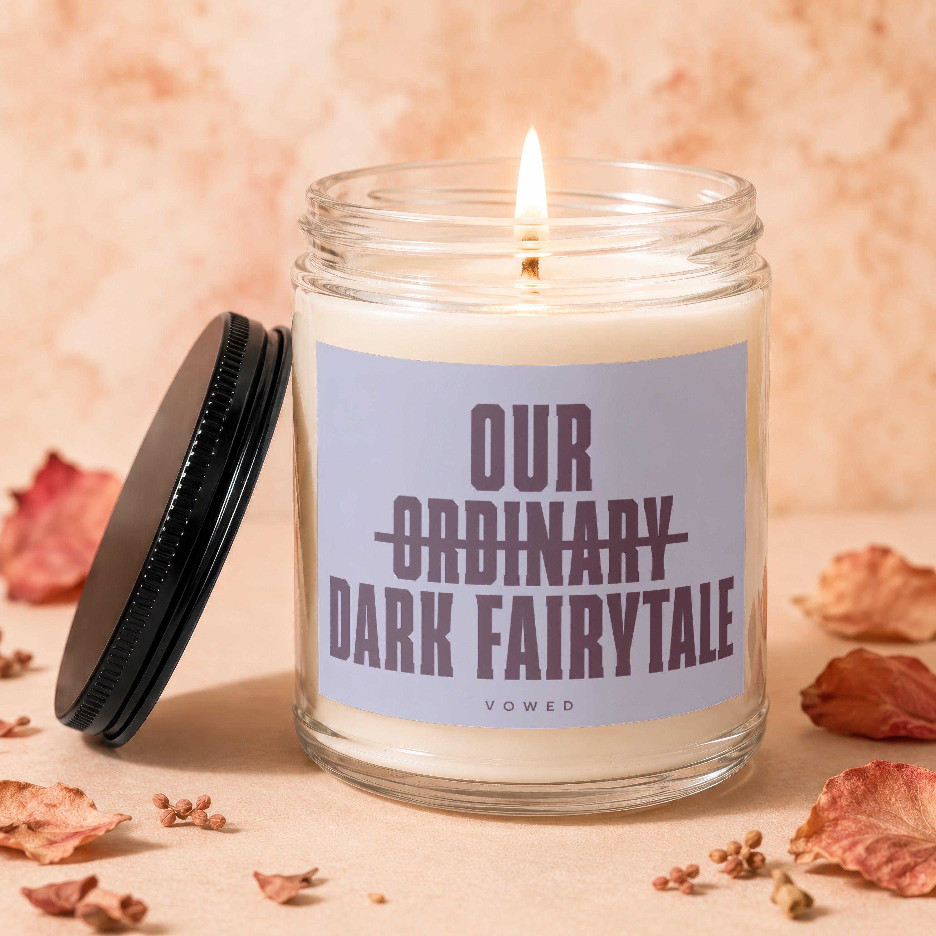 Candle with "Our Ordinary Dark Fairytale" text burns next to its lid.