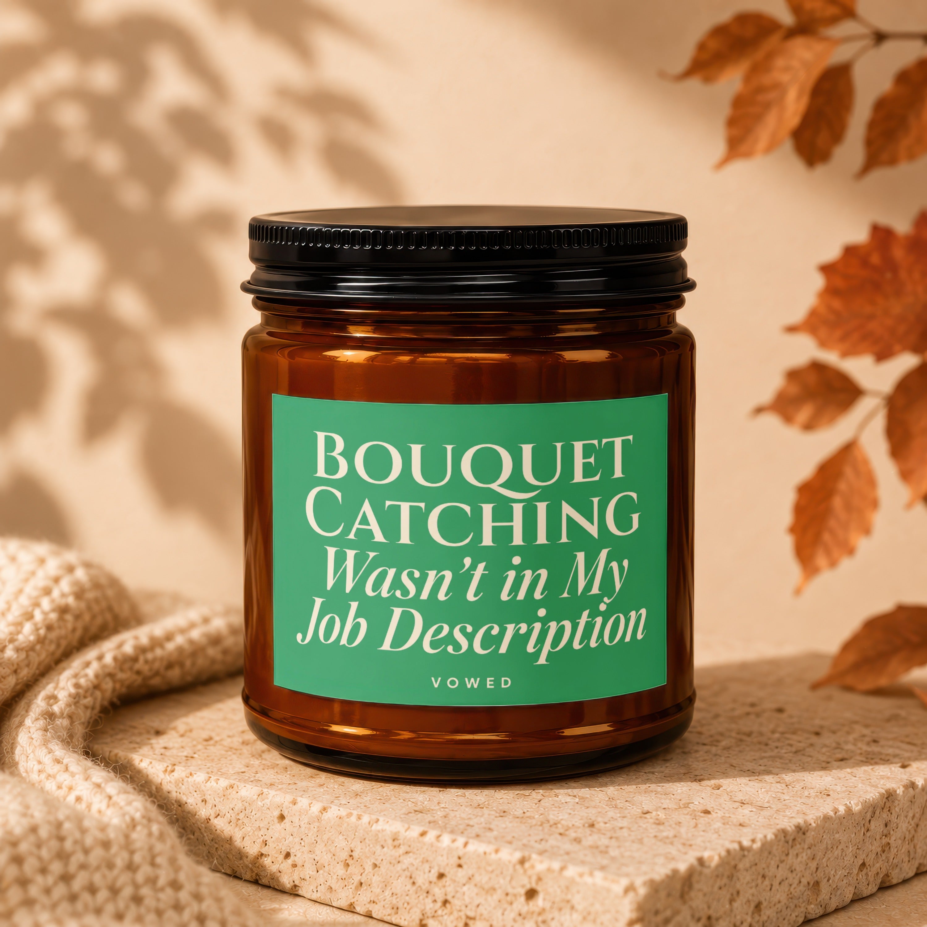 Amber glass candle with green label reading "BOUQUET CATCHING Wasn't in My Job Description VOWED".