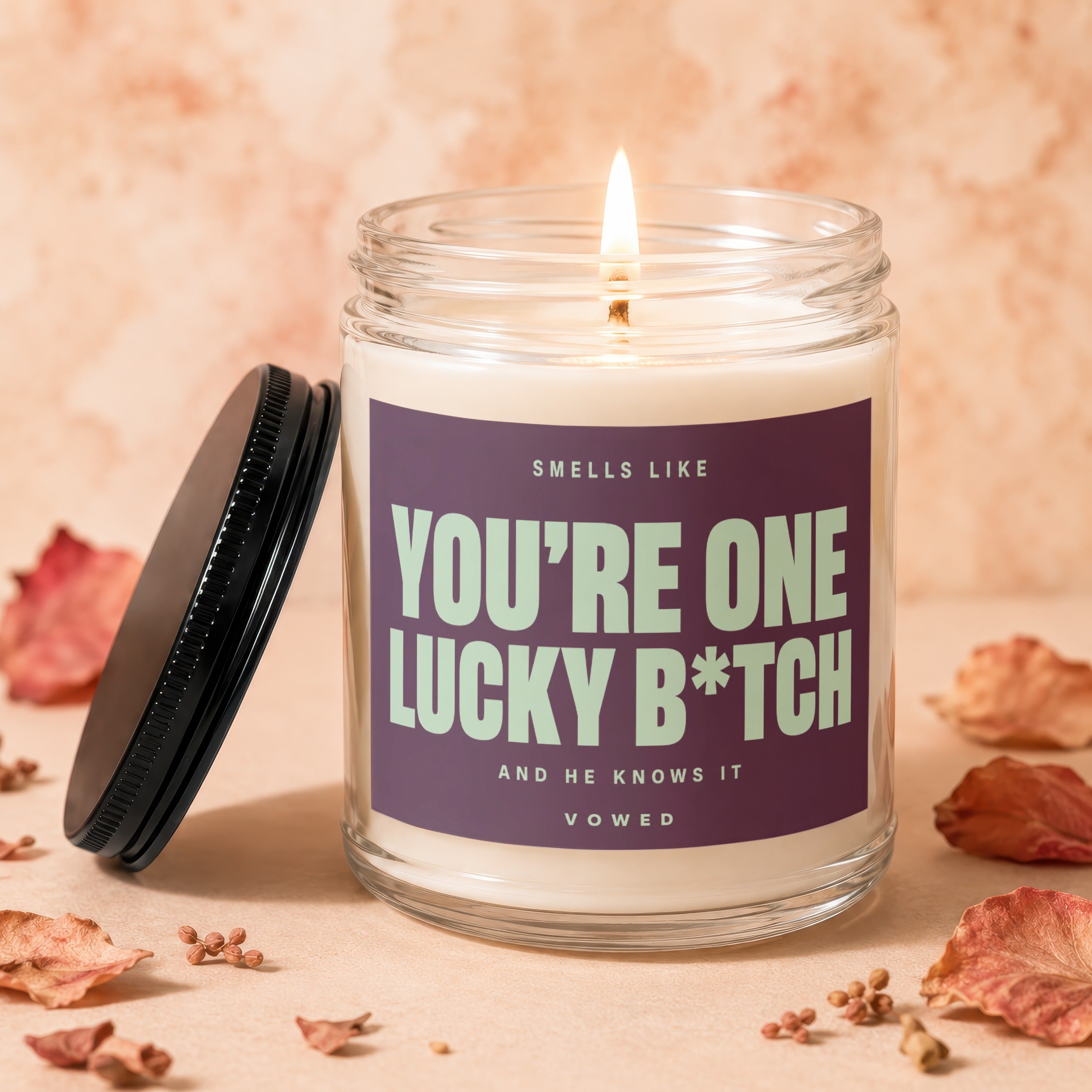 Candle with lit wick and label reading "You're one lucky b*tch and he knows it".
