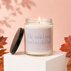 Lit candle in glass jar with text "He said yes (and so did he)" on a pink background.