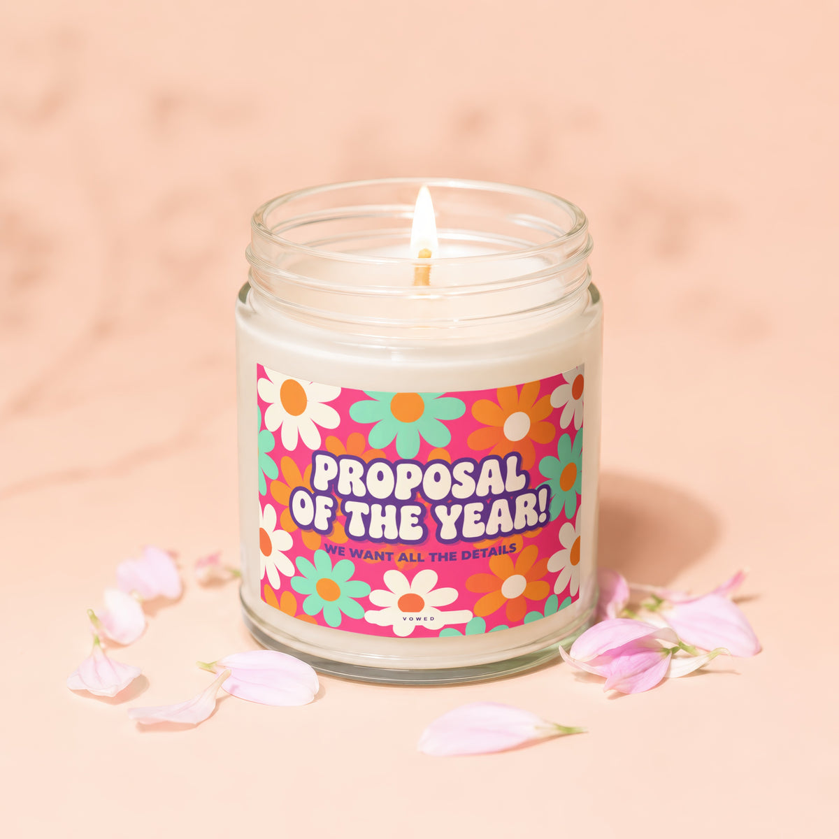 Lit candle with "Proposal of the Year! We Want All the Details" text on a floral label.