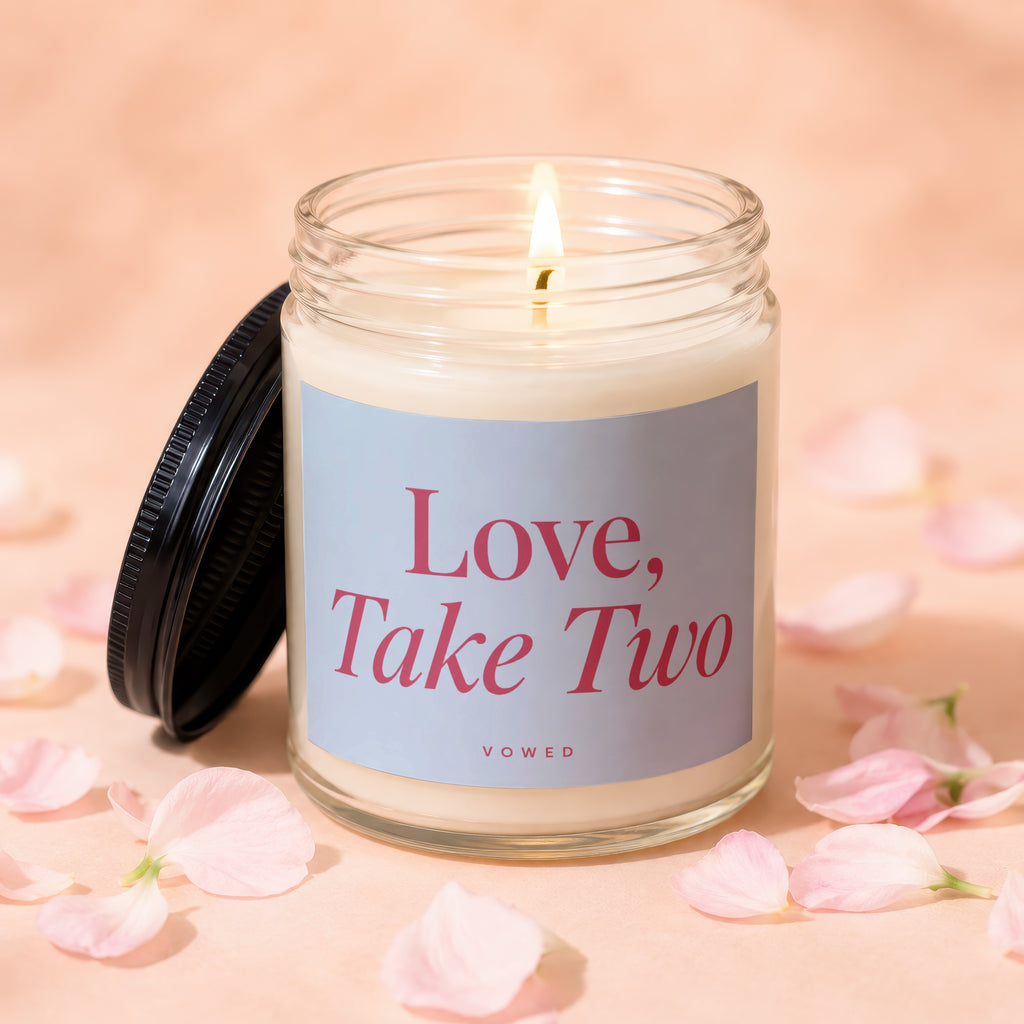 Candle labeled "Love, Take Two" surrounded by scattered pink petals.