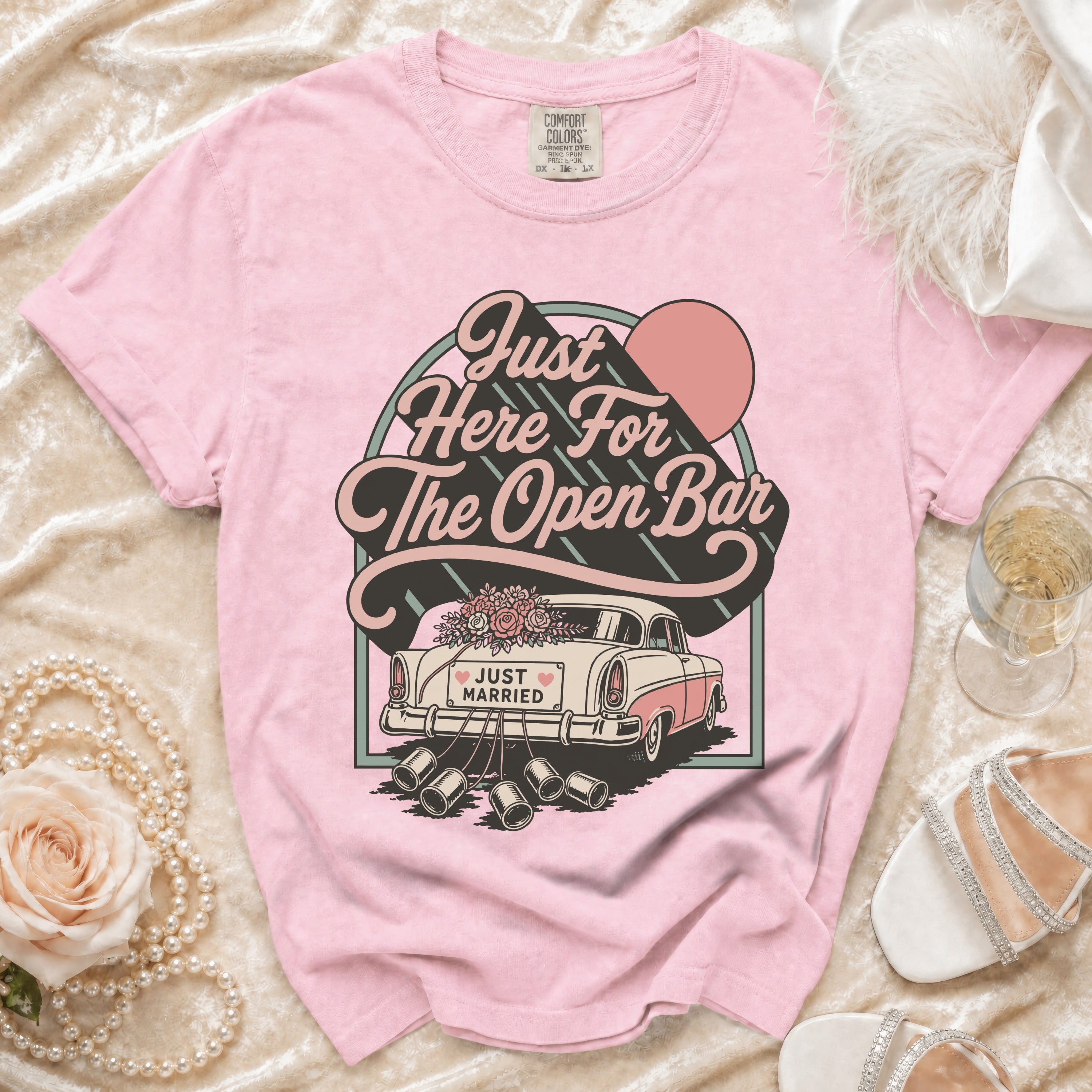 Pink t-shirt with retro graphic of a "Just Married" car and "Just Here For The Open Bar" text.