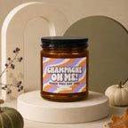 Amber glass candle with "Champagne On Me! When You Say Yes!" label.