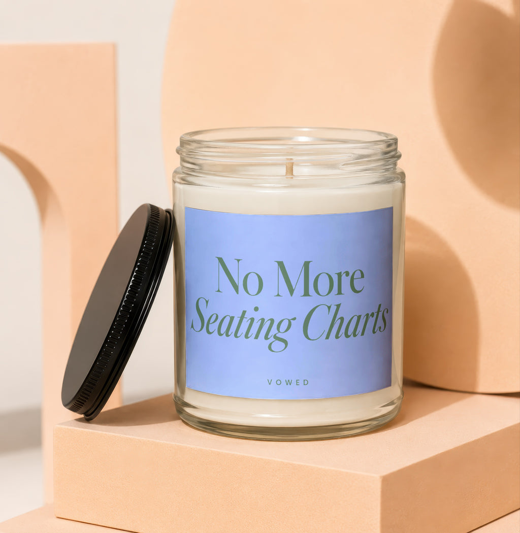 Glass jar candle with "No More Seating Charts" and "VOWED" text on a blue label.