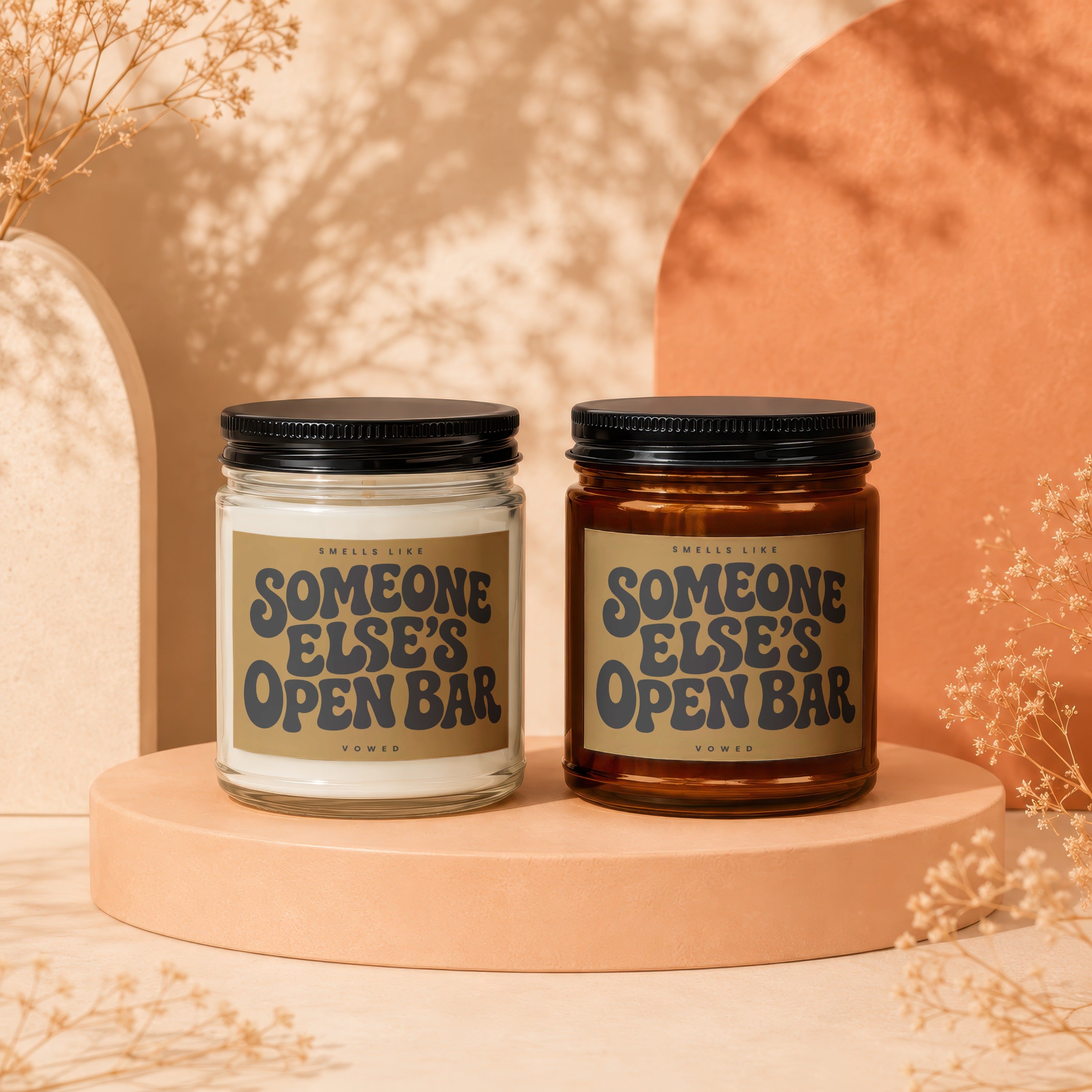 Two candles labeled "Smells Like Someone Else's Open Bar" displayed on pedestals.