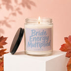 Glass candle with lit wick, label reads "Bride Energy Multiplied VOWED".