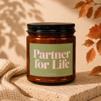Amber glass candle with a light green label that says "Partner for Life" and "VOWED".