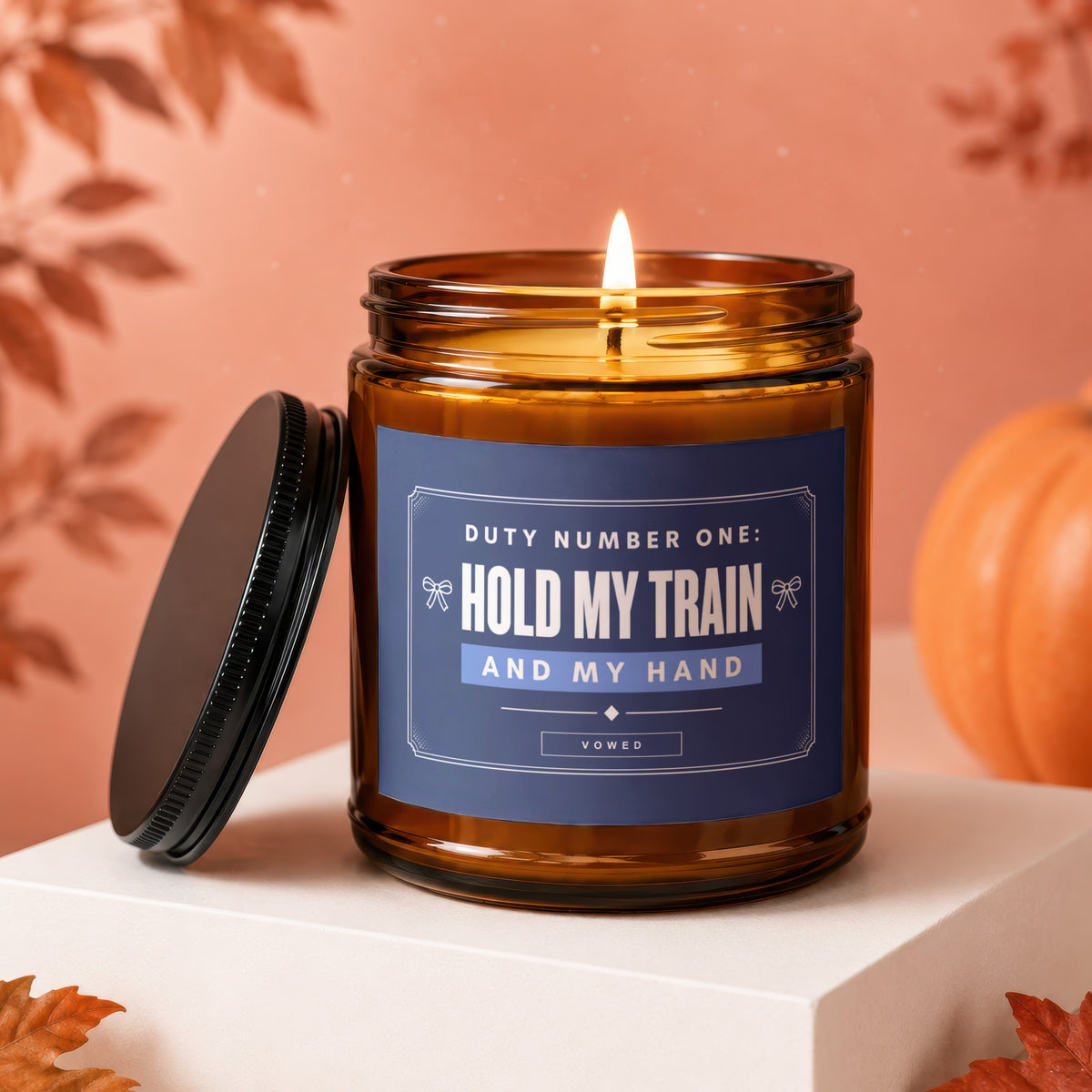 Amber jar candle with lid off, labeled "Hold My Train And My Hand".