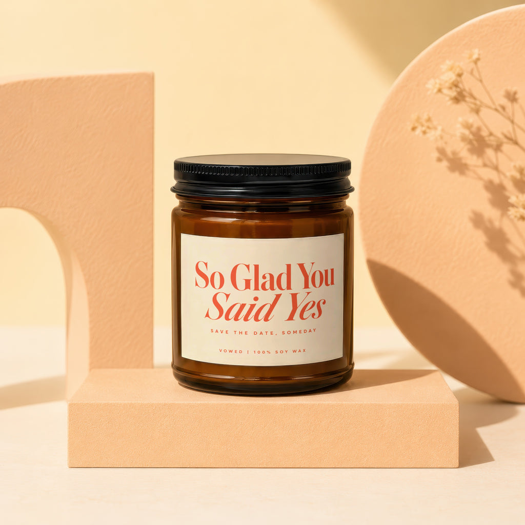 Amber jar candle labeled "So Glad You Said Yes" with "100% Soy Wax".