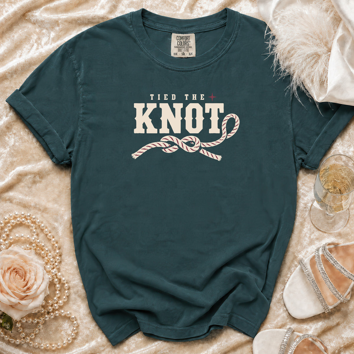 Teal t-shirt with "Tied the Knot" and rope knot graphic, laid flat.