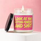 Lit candle in a glass jar with pink label reading "LOOK AT YOU GETTING MARRIED AND SHIT".
