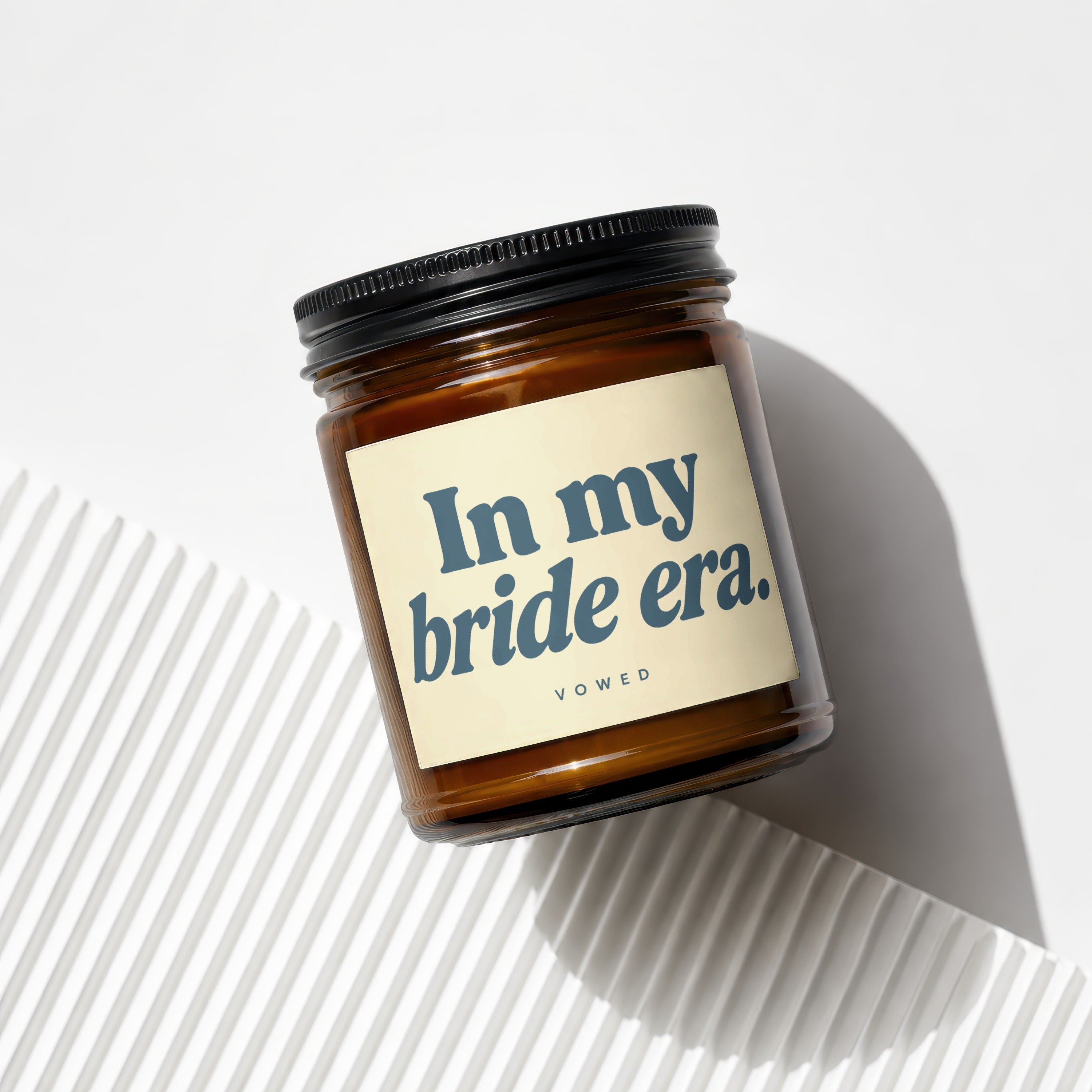 Amber glass candle with a cream label reading "In my bride era." and "VOWED".