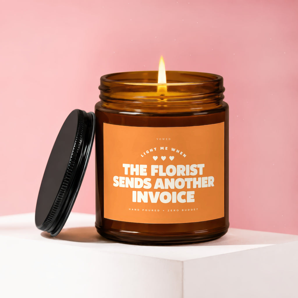 Amber candle with burning wick, reads "The Florist Sends Another Invoice."