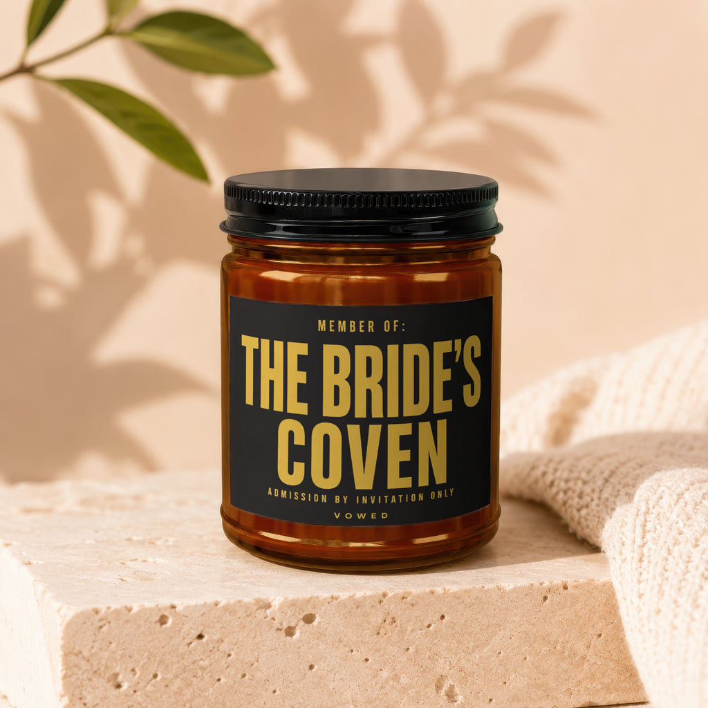 Amber jar candle with black lid, "The Bride's Coven" text, admission by invitation only.