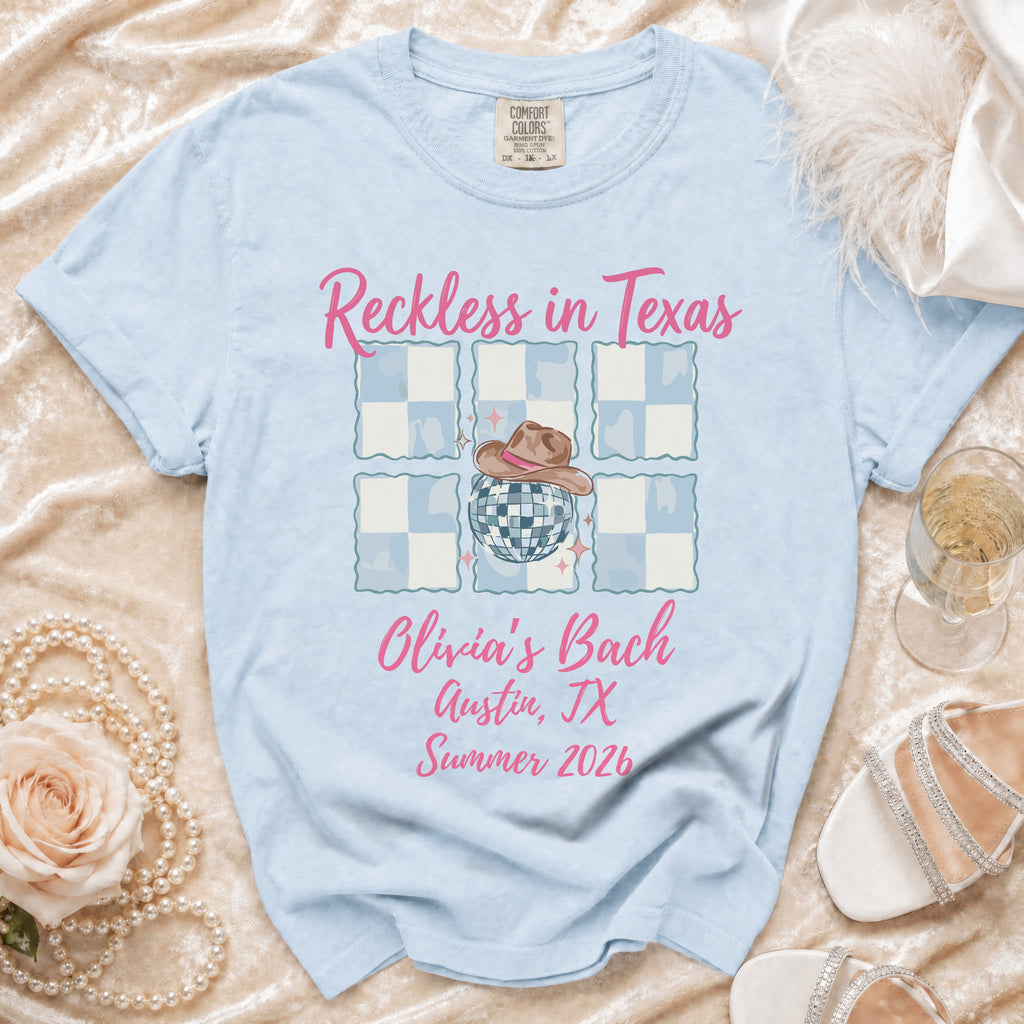Light blue t-shirt with "Reckless in Texas Olivia's Bach Austin, TX Summer 2026" text.