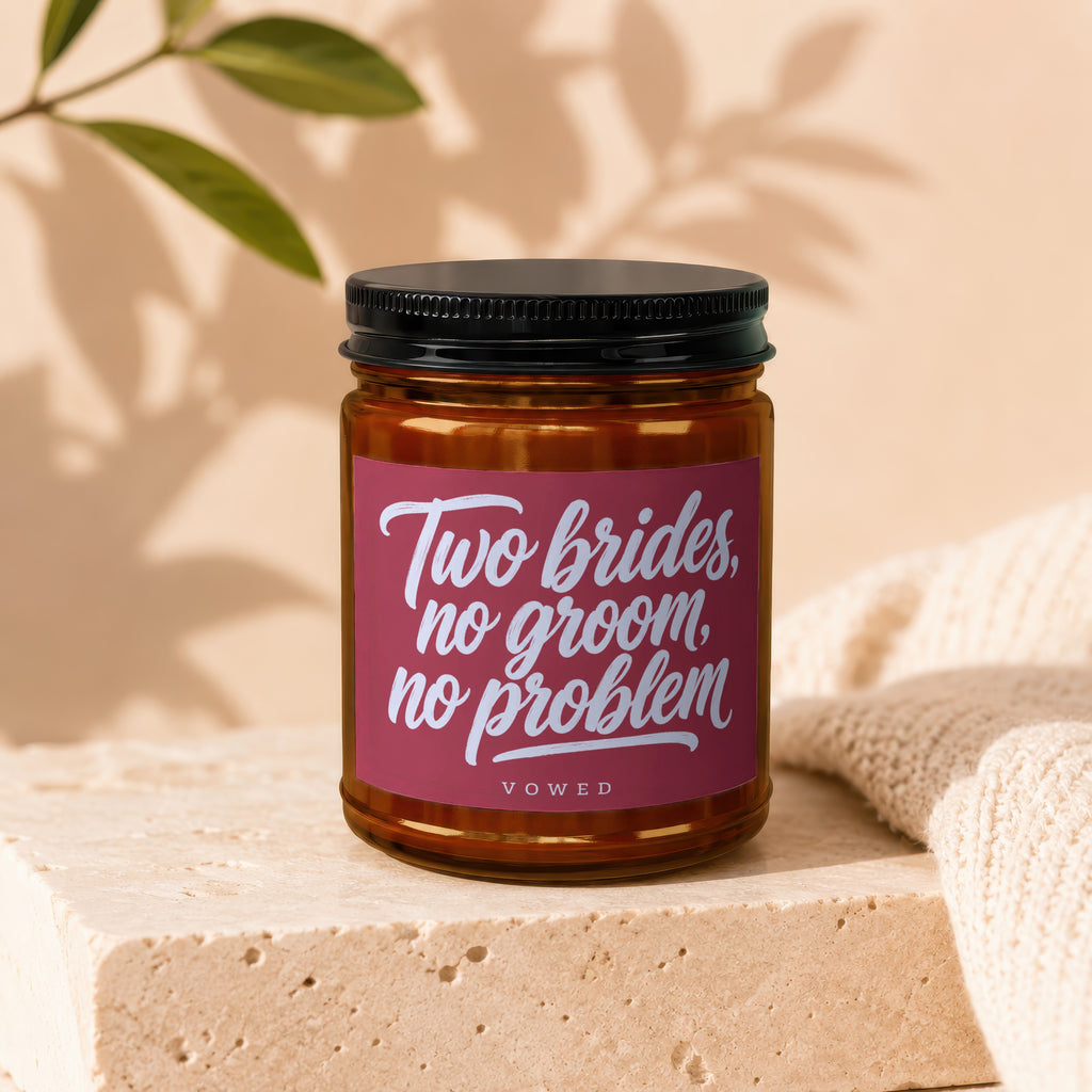 Amber candle with pink label reading "Two brides, no groom, no problem" and "VOWED".