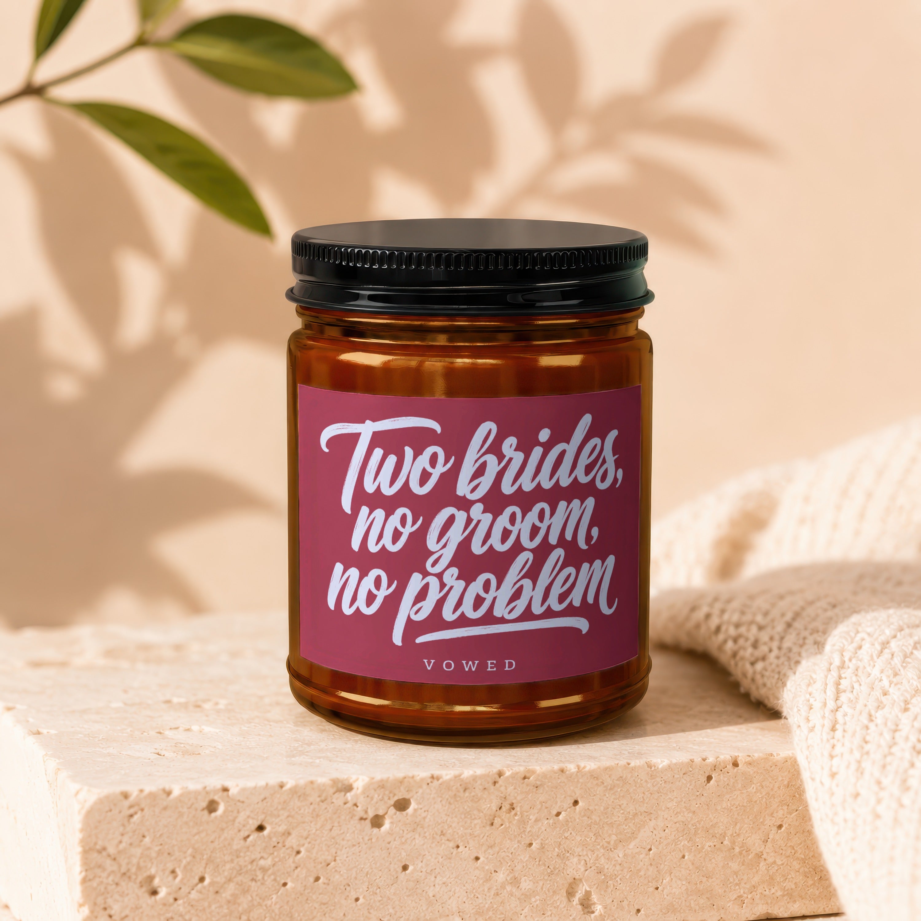 Amber candle with pink label reading "Two brides, no groom, no problem" and "VOWED".