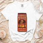White t-shirt with "Reckless in Texas" matchbook graphic, Olivia's Bach, Austin, TX, Summer 2026.