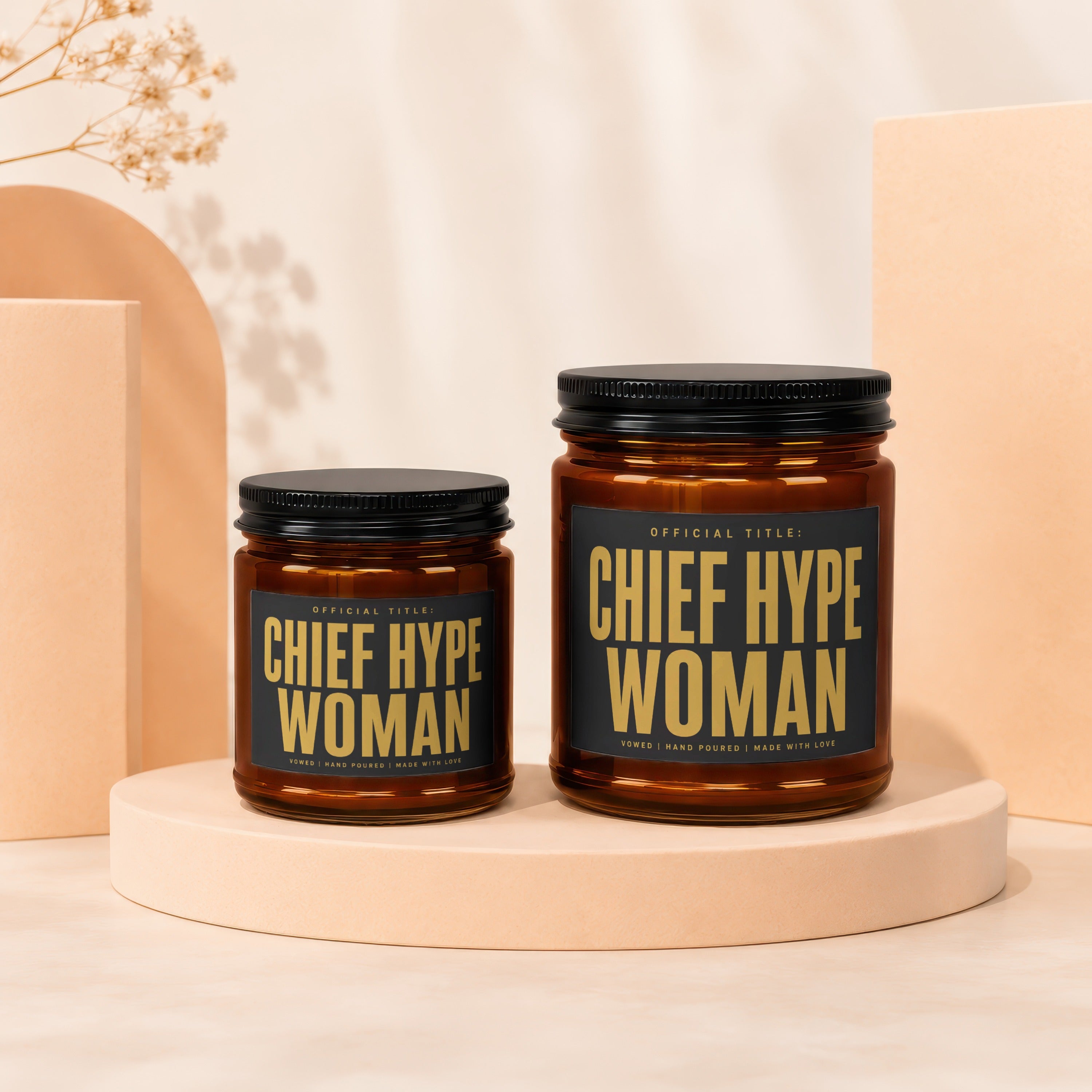 Two amber glass candles with black lids and black labels reading "Chief Hype Woman".