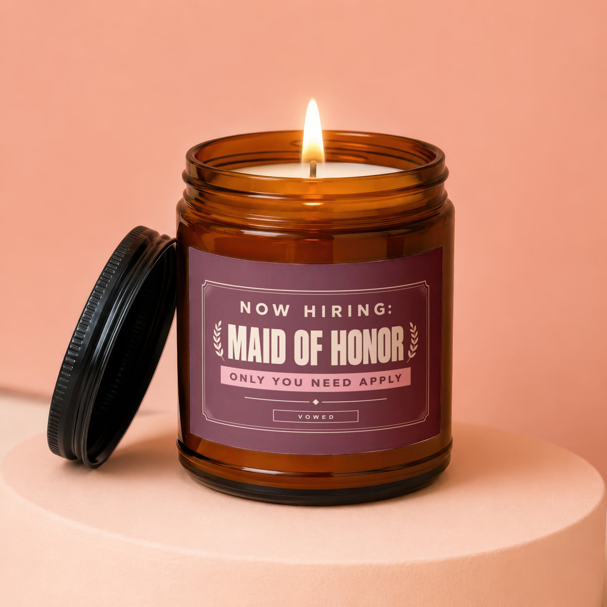 Amber candle with lit wick and lid off, reads "Now Hiring: Maid of Honor".