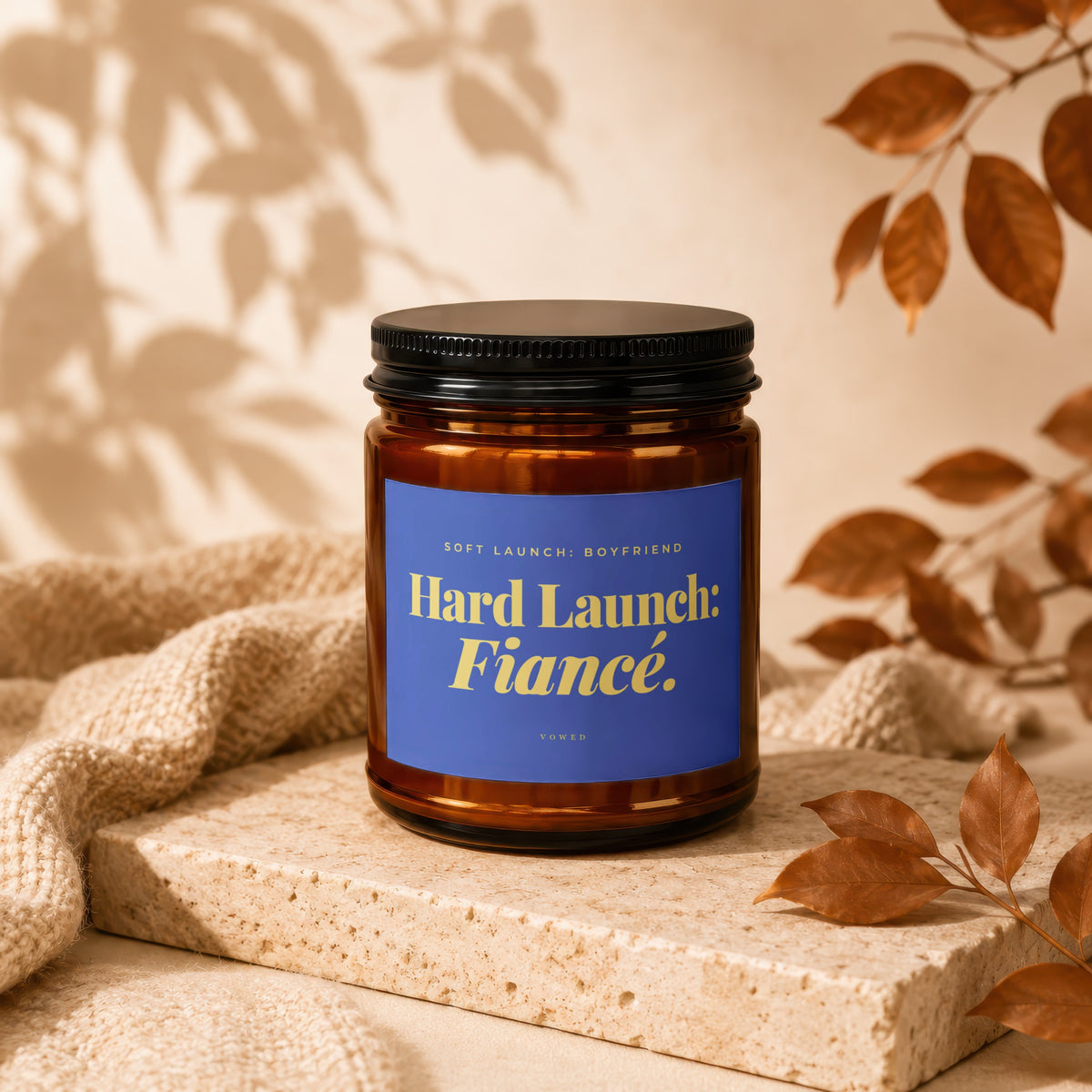 Amber jar candle with blue label reading "Hard Launch: Fiancé."