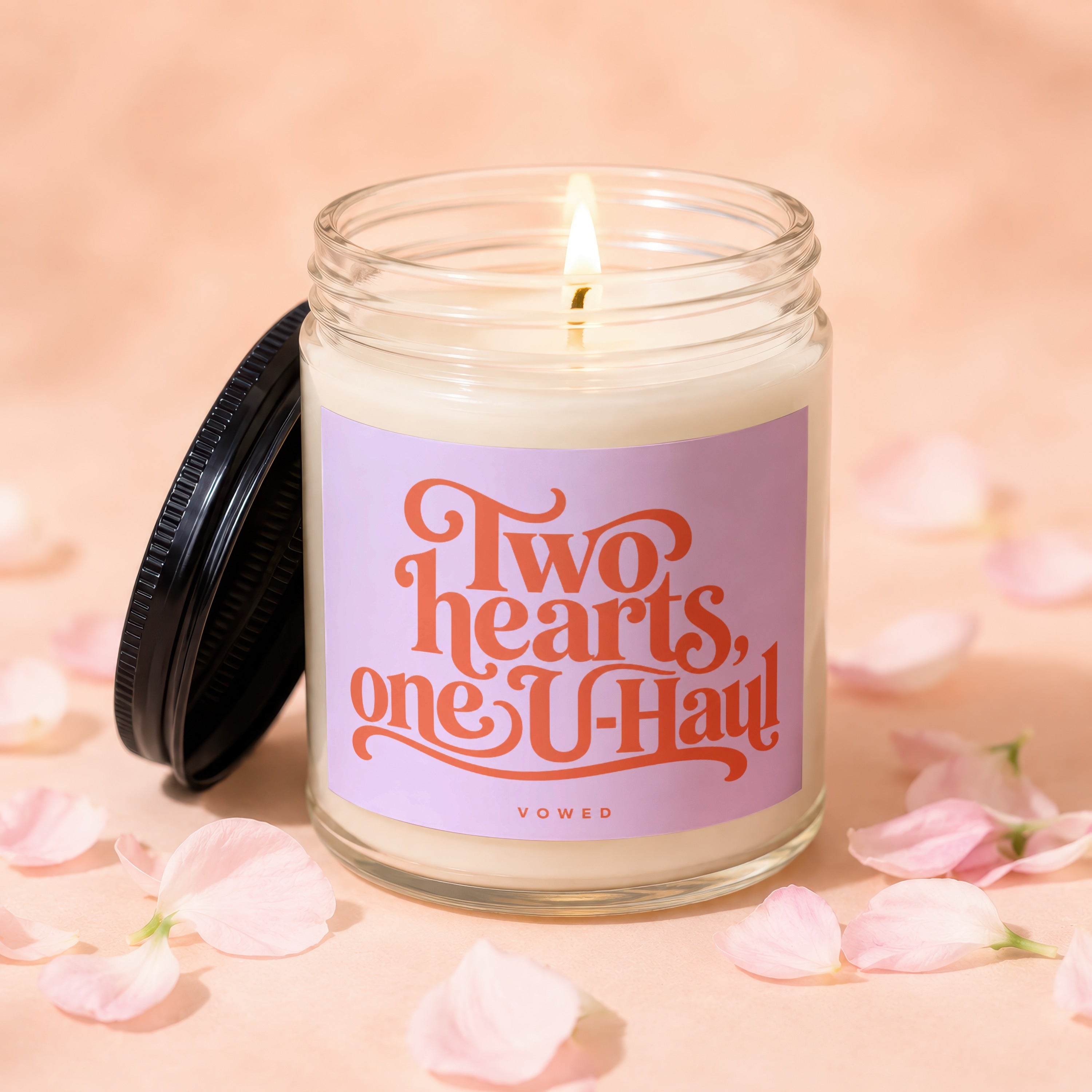 Lit candle with a label reading "Two hearts, one U-Haul" surrounded by pink petals.