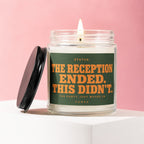 Glass candle with lit wick, label reads "STATUS: THE RECEPTION ENDED. THIS DIDN'T."