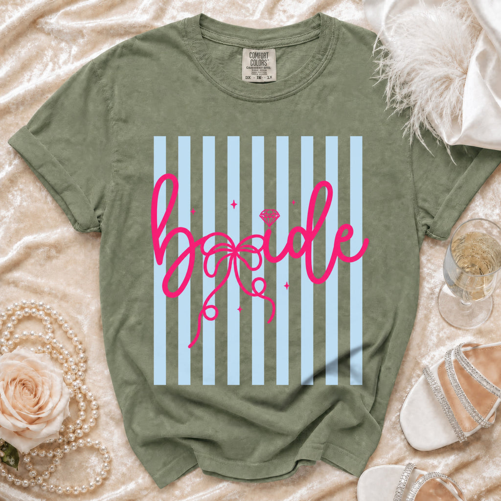 Green t-shirt with pink "bride" text on a light blue striped background.