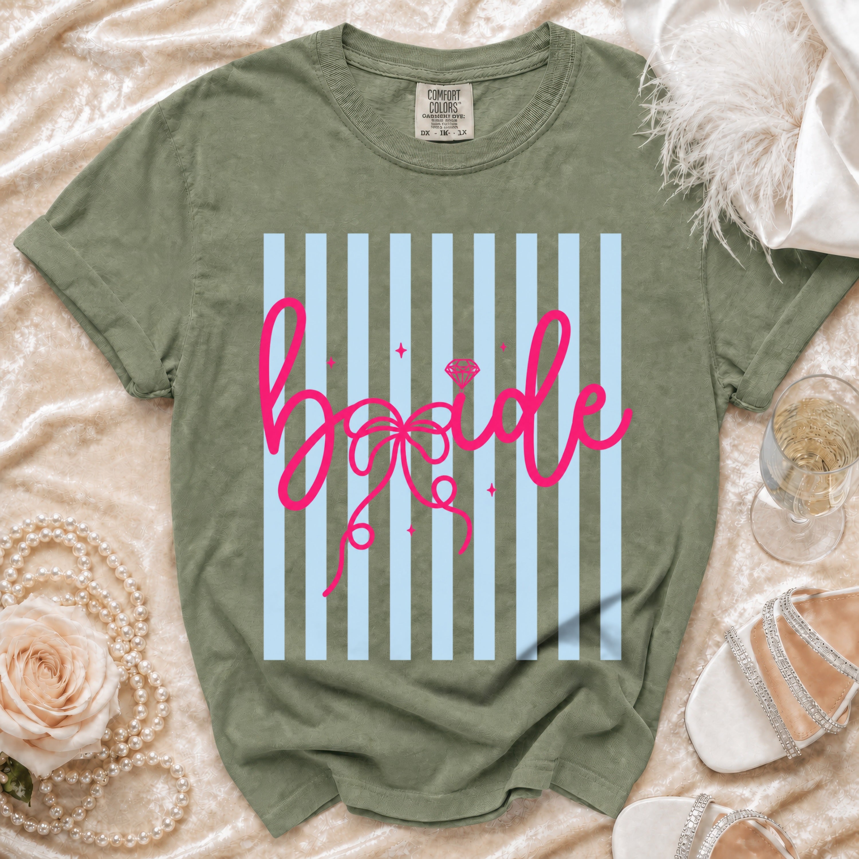 Green t-shirt with pink "bride" text on a light blue striped background.