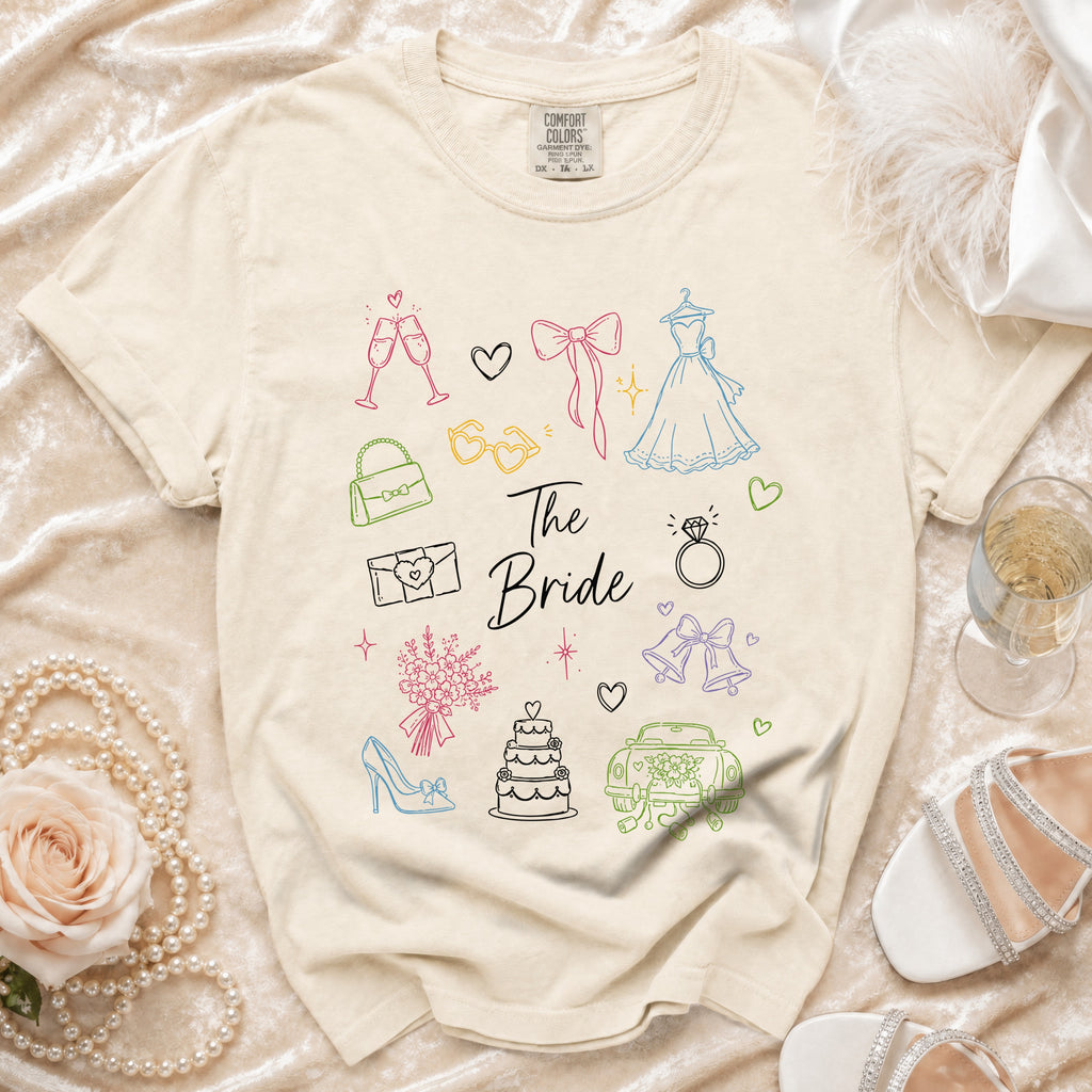 Unisex beige t-shirt with outline graphics of wedding items and "The Bride" text.