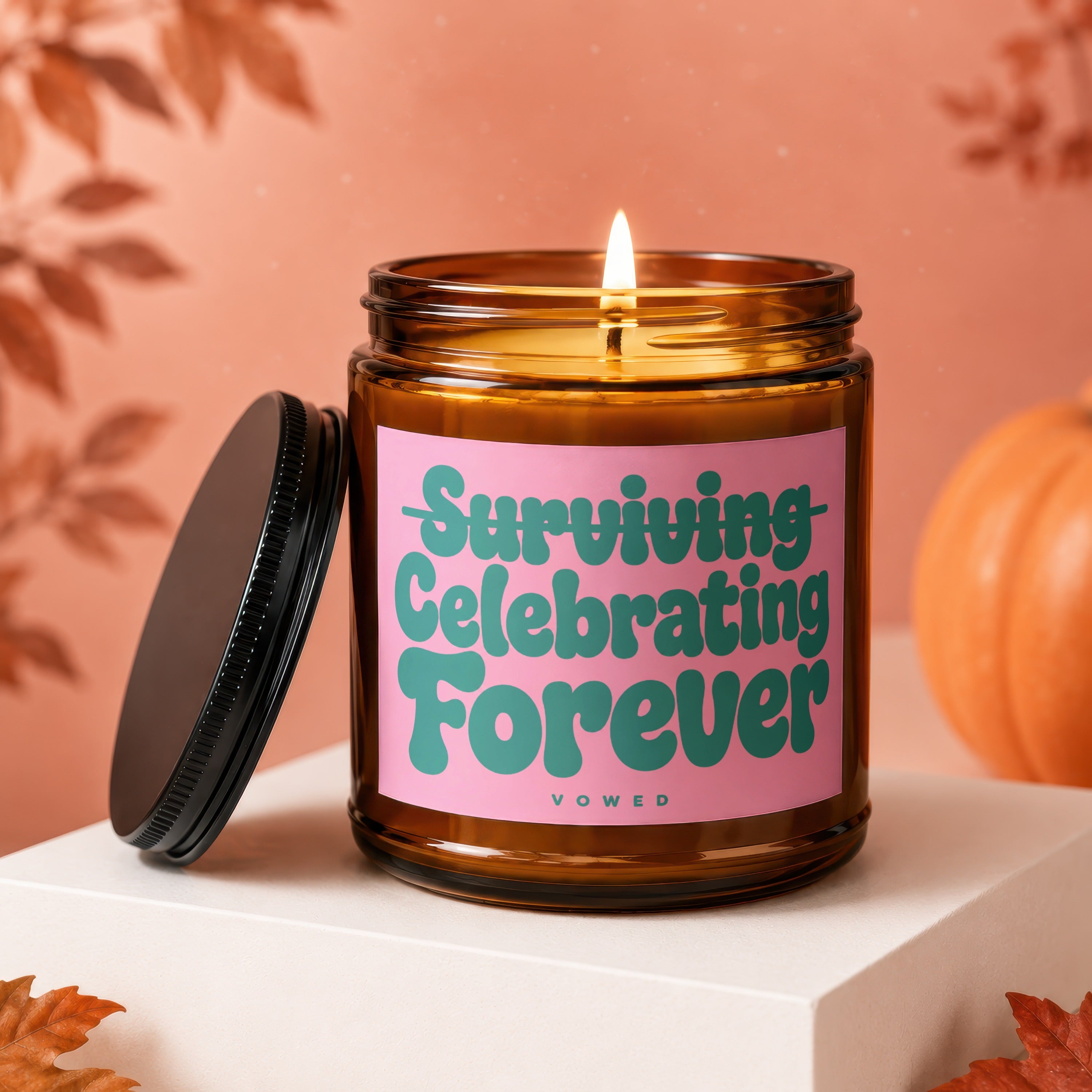 Amber candle with pink label reading "Surviving Celebrating Forever Vowed"