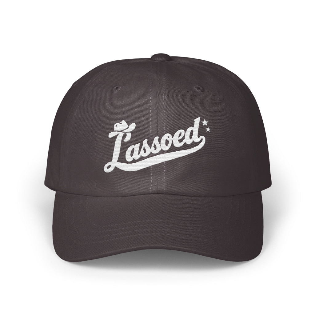 Dark gray dad hat featuring white cursive embroidery of the word Lassoed with a cowboy hat and stars.