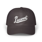 Dark gray dad hat featuring white cursive embroidery of the word Lassoed with a cowboy hat and stars.