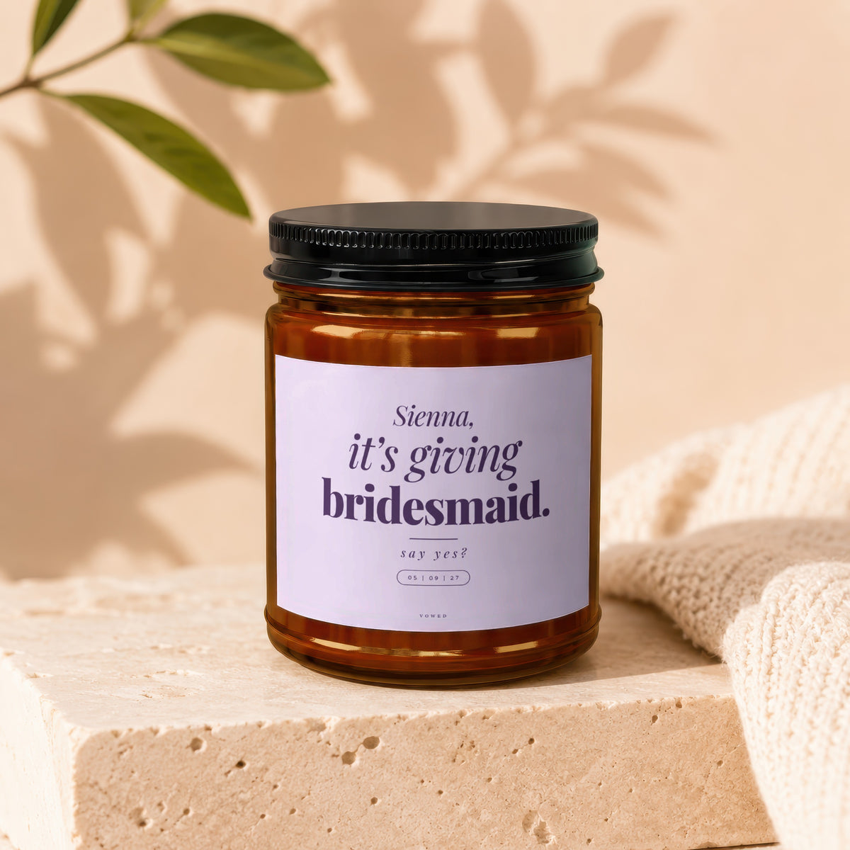 Candle with a label reading "Sienna, it's giving bridesmaid. say yes?"