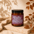 Amber candle with pink label that reads "Enby Engaged Vowed".