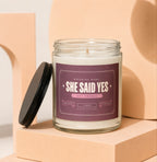 Glass jar candle with "She Said Yes" label.