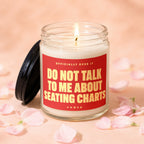 Glass jar candle with lit wick and red label reading "Do Not Talk To Me About Seating Charts".
